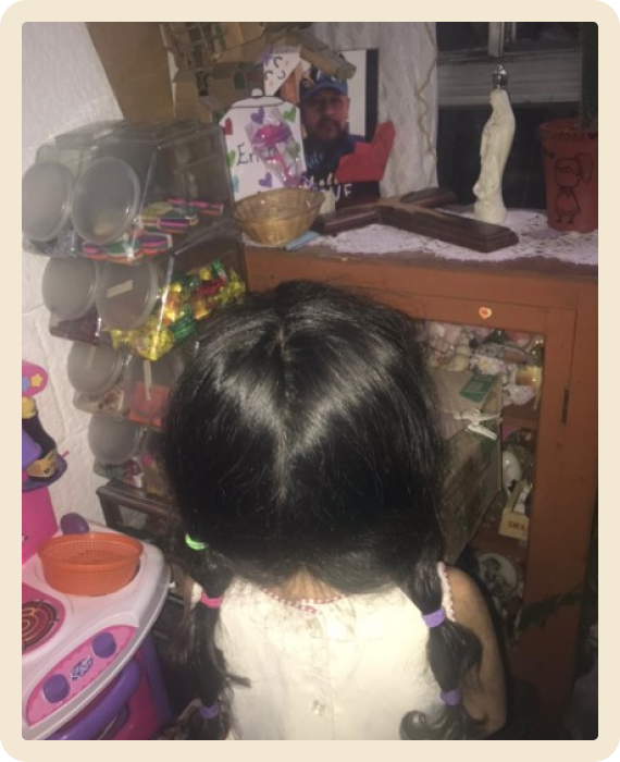 Niña de espalda peinada con dos trenzas mirando la foto de su papá