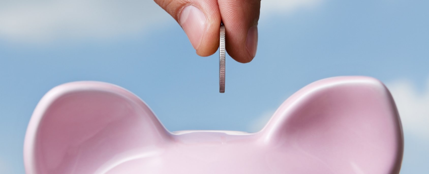 Mano depositando dinero en una alcancía